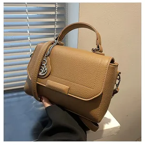 Detailed texture of brown pebble leather handbag with silver swan pendant charm