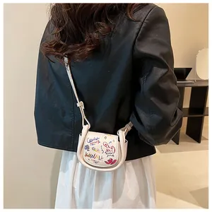 Détail d'un mini sac selle blanc avec des motifs graffiti colorés dessinés à la main