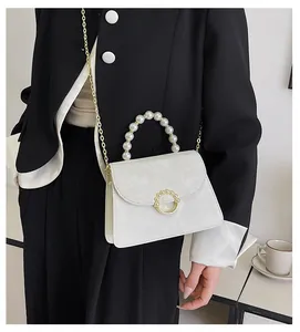 Detail of elegant cream-white pearl handle mini bag with gold chain and pearl buckle