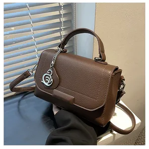 Close-up of deep brown lychee grain leather handbag with silver swan charm detail