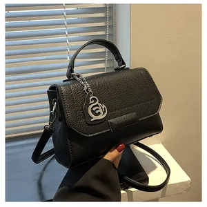 Detail of black lychee grain handbag featuring silver hardware and a decorative metal pendant
