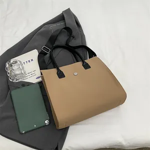 Detail view of khaki tote bag with black handles and silver magnetic buckle closure