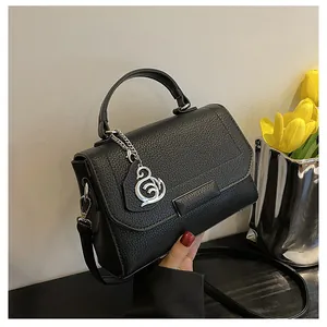 Detail view of black lychee leather handbag with elegant silver swan pendant and handle