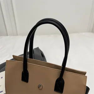 Detail of camel leather tote bag with silver round buckle and black cylindrical handles