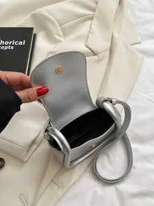 Mini sacoche de selle argentée avec fermoir magnétique doré sur une veste blanche