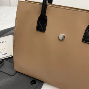 Close-up of khaki tote bag showing silver magnetic snap and precise cross-stitching details