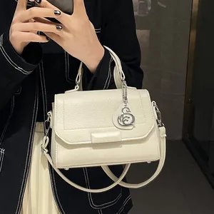 Creamy beige pebbled leather handbag with silver hardware and logo charm on top handle
