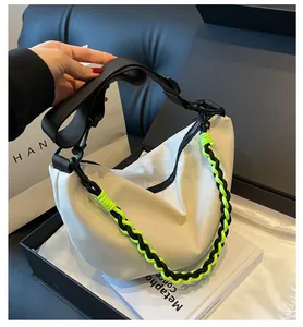 Detail of off-white nylon crescent bag with vibrant neon green woven chain and strap
