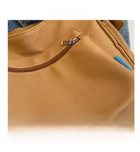 Detail shot of brown canvas tote bag with metal zipper pocket and canvas label