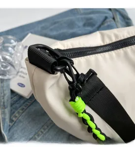Detail of durable black metal hook and green braided pull cord on a nylon shoulder bag