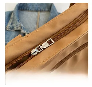Detail view of smooth silver metal zipper and nylon fabric texture on a brown tote bag