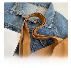 Detail of reinforced double-stitched canvas handles on a brown tote bag for women