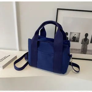 Detail view of navy blue canvas handbag with adjustable straps and sturdy zip closure