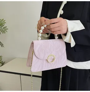 Detail of pink pleated crossbody bag with pearl handle and golden ring buckle closure