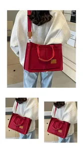 Dettaglio borsa tote in tela rossa con ampia tracolla e patch logo in pelle frontale