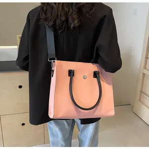 Rear view of model wearing a pink fashion tote bag with black straps in a minimalist setting