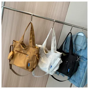 Detailed view of high-density canvas tote bags in khaki, white, and black with side pockets