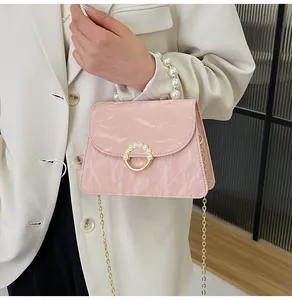 Pink pleated patent leather handbag detail with pearl handle and golden chain strap