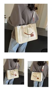 Dettaglio della borsa tote in tela con doppie tasche frontali e manici in pelle marrone