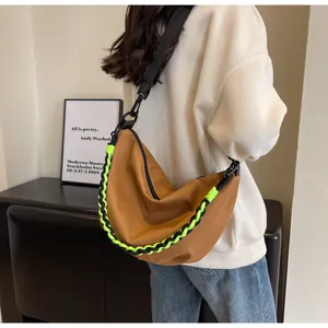 Close-up of brown nylon crescent bag with neon green woven rope handle and wide strap