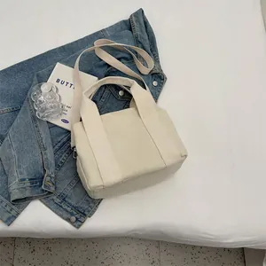Flat lay of minimalist cream canvas tote bag with adjustable shoulder strap on white fabric