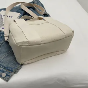 Detail of minimalist cream canvas tote bag with adjustable strap and reinforced stitching