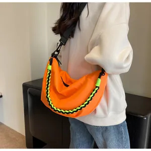 Detail of bright orange nylon dumpling bag with black and neon green woven chain strap