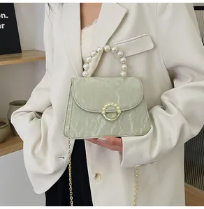 Detailed view of the light green marble textured bag with a large pearl handle and gold chain