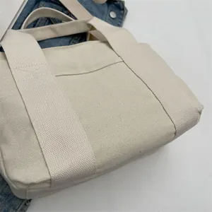 Close-up of beige canvas handbag showing neat stitching and functional front pocket detail