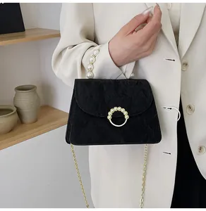 Detail of crossbody bag with pearl handle, ring buckle, and pleated fabric texture