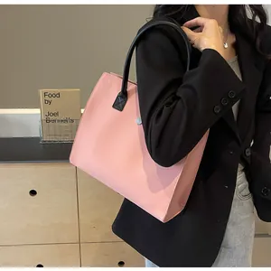 Detailed shot of a pink tote bag with black tubular handles for stylish office commuting