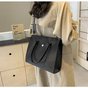 Detail view of black nylon tote bag with silver buckle and removable wide shoulder strap