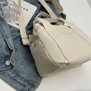 Overhead view of off-white canvas tote bag with adjustable strap and side metal D-ring detail