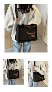 Dettaglio della borsa tote in tela nera con doppie tasche frontali e finiture in pelle marrone