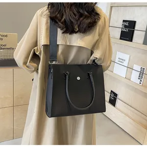Detail of black large tote bag with adjustable wide nylon shoulder strap on model back