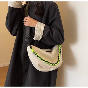 Detail of off-white crescent crossbody bag with vibrant neon woven chain and nylon strap