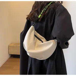 Detail of off-white nylon crescent bag featuring black and green woven shoulder strap