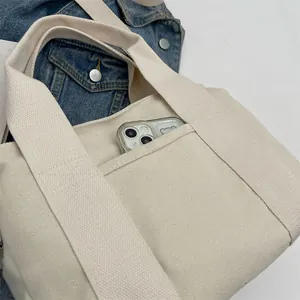 Macro shot of cream canvas tote bag showing outer pocket for smartphone storage
