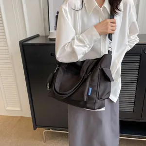 Detailed view of black canvas tote bag with adjustable strap and matching small pouch