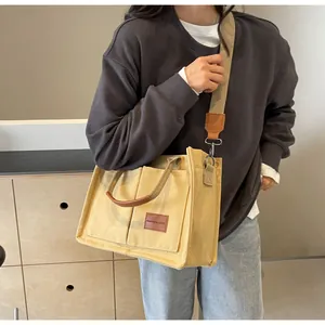Dettaglio della borsa tote in tela gialla con finiture in pelle marrone ed etichetta