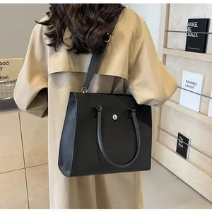Rear view of model wearing a black matte tote bag with wide nylon strap and silver buckle