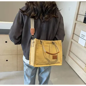 Dettaglio della borsa tote in tela gialla con manici in pelle e tracolla regolabile