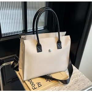 Detailed view of cream beige tote bag with silver buckle and adjustable black shoulder strap