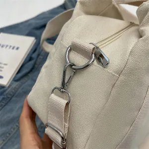 Close-up of high-quality silver metal hook and zipper on cream canvas handbag