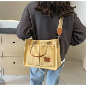Dettaglio della borsa tote in tela gialla con tasche grandi e cinturini in pelle marrone