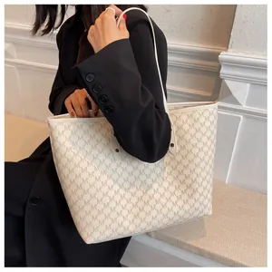 Dettaglio di una grande borsa tote monogramma con motivi M indossata da una modella