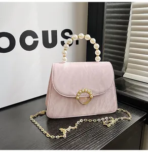 Detail of pink pleated bag with elegant pearl handle and circular pearl flip-lock