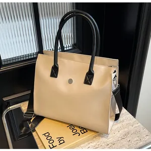 Detail view of cream tote bag featuring black cylindrical handles and silver metal buckle