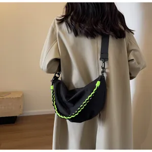 Close-up of a black crescent nylon crossbody bag with neon green woven rope detailing