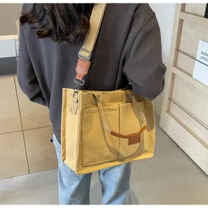 Dettaglio della borsa tote in tela gialla con tracolla regolabile e tasche frontali